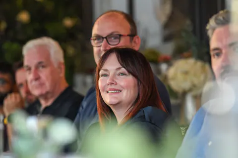 A guest smiling as she listens at the dinner table.
