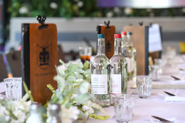 The dinner table laid with carved wooden menu boards, water bottles and white flowers.