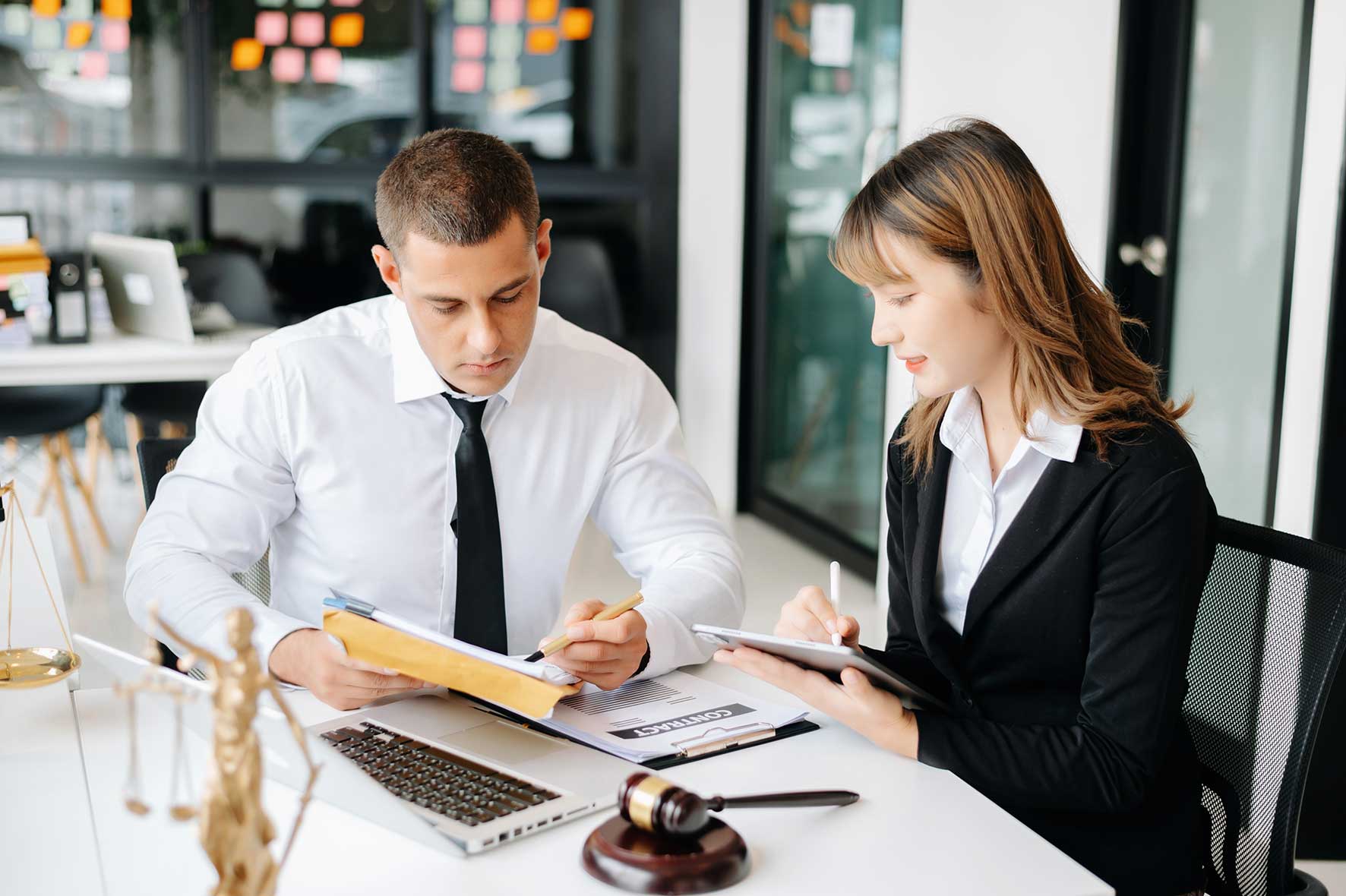 Two professionals reviewing a contract at an office desk.